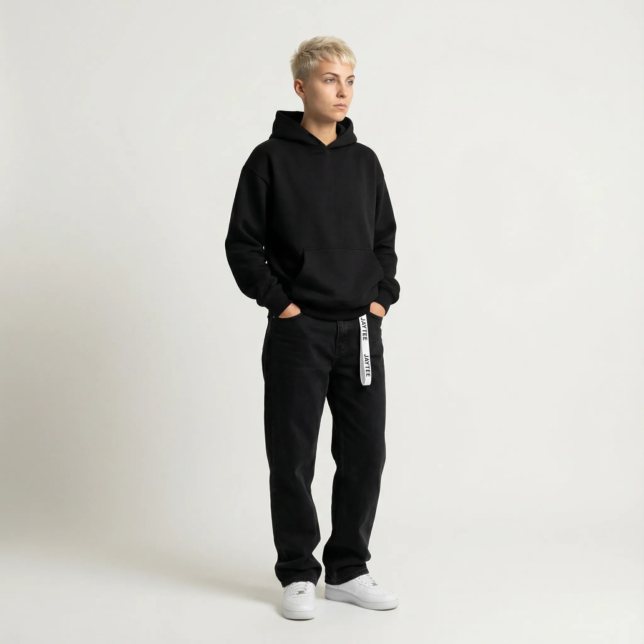Person wearing a black JAYTEE hoodie and black pants with white text on a white background