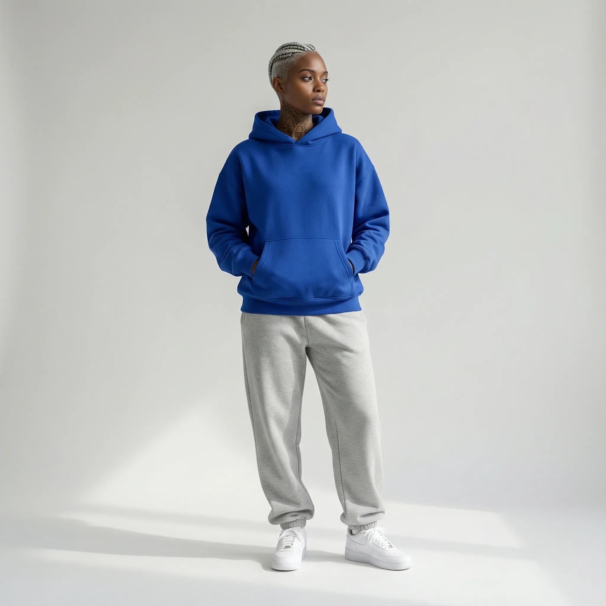 Person wearing a blue JAYTEE hoodie and gray sweatpants on a white background