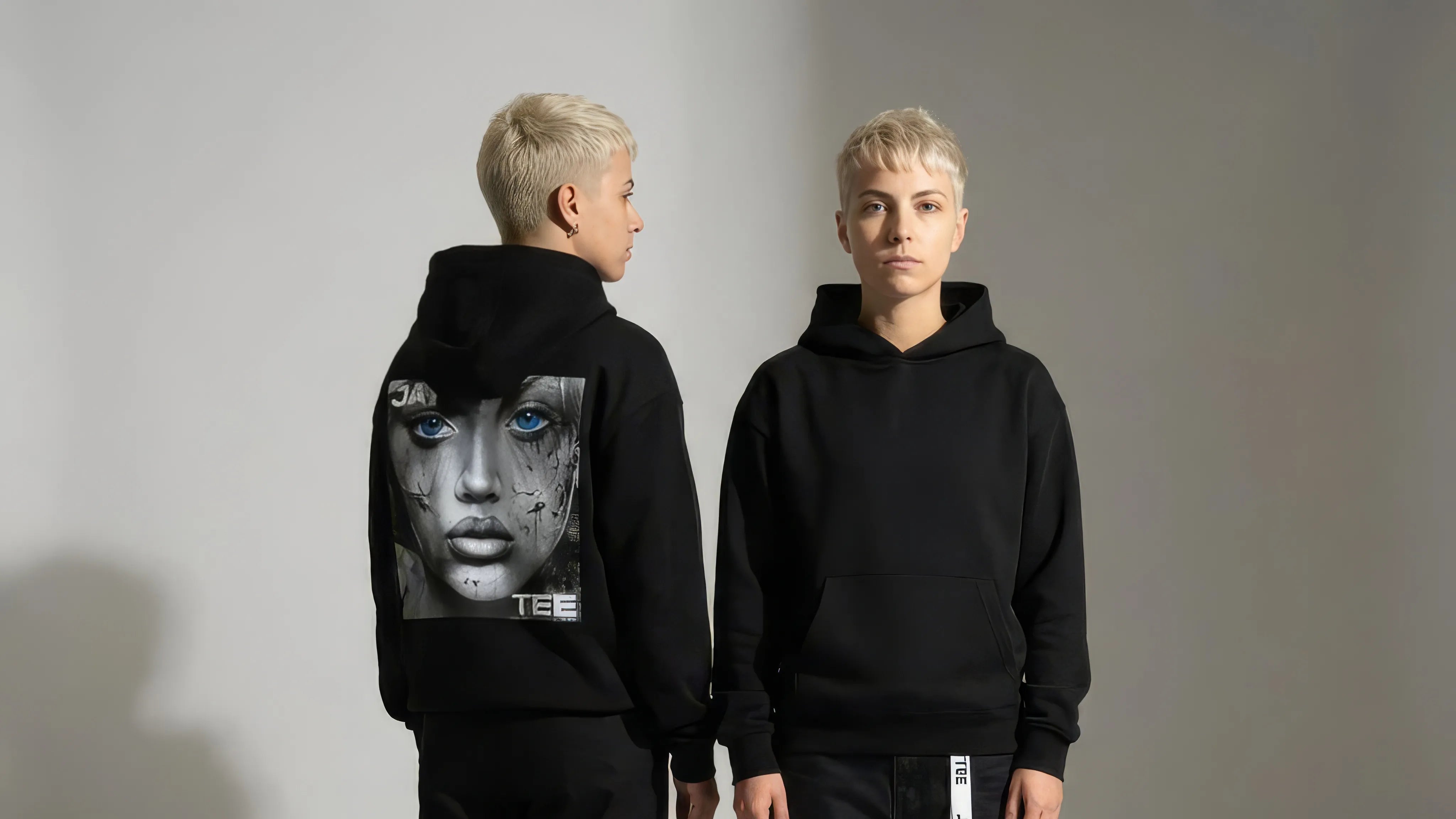 Person wearing a black JAYTEE hoodie with a graphic design on the back, standing against a plain background.