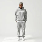 Person wearing a gray JAYTEE hoodie and pants on a white background