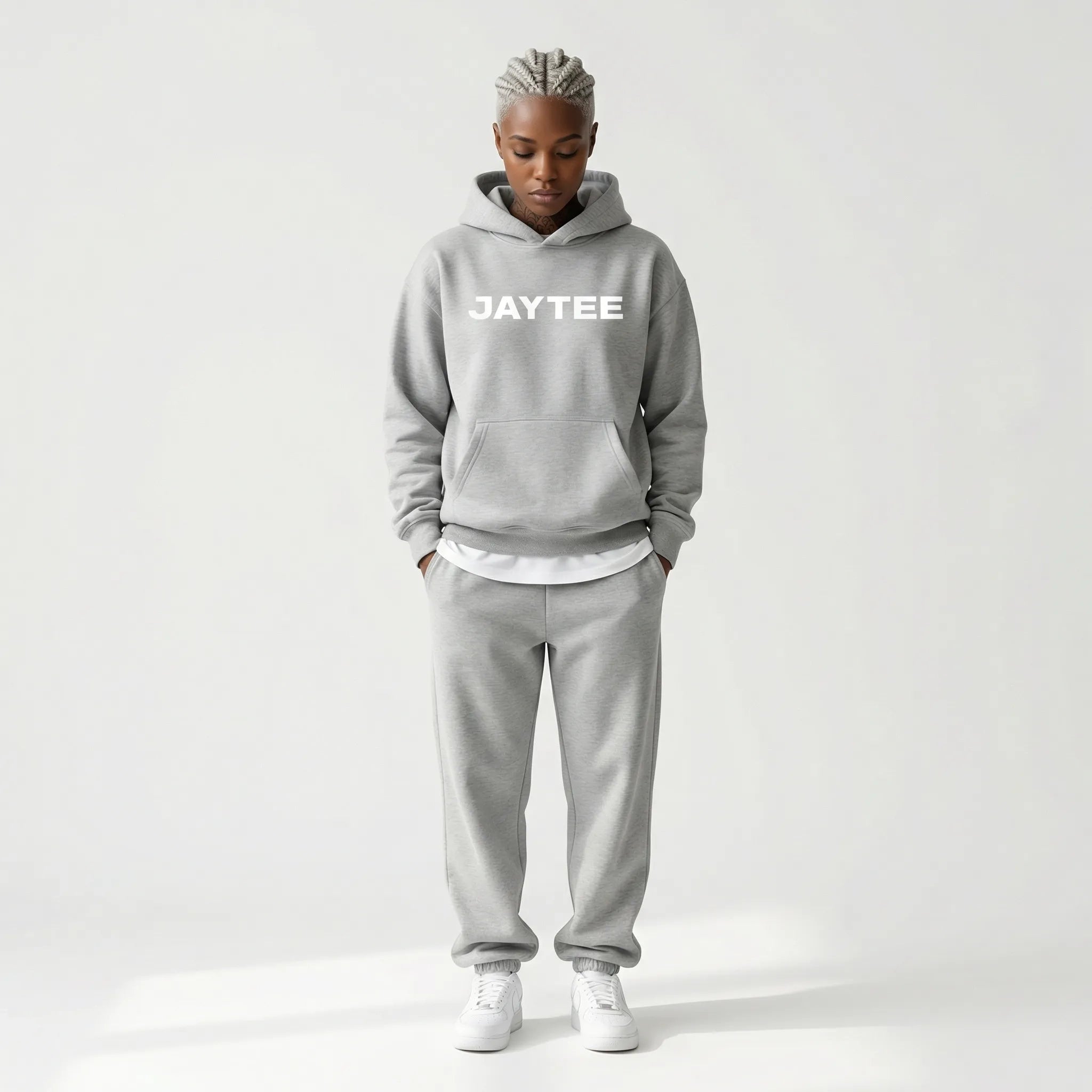 Person wearing a gray JAYTEE hoodie and pants on a white background