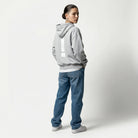 Person wearing a gray JAYTEE hoodie and blue jeans on a white background
