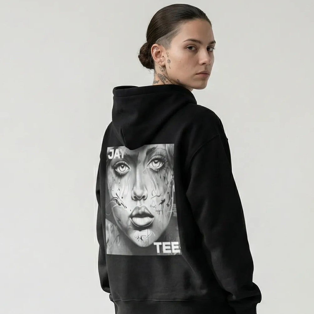 Person wearing a black JAYTEE hoodie with a graphic design on the back, standing against a white background