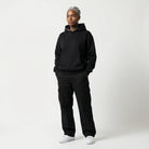 Person wearing a black JAYTEE hoodie and pants on a white background