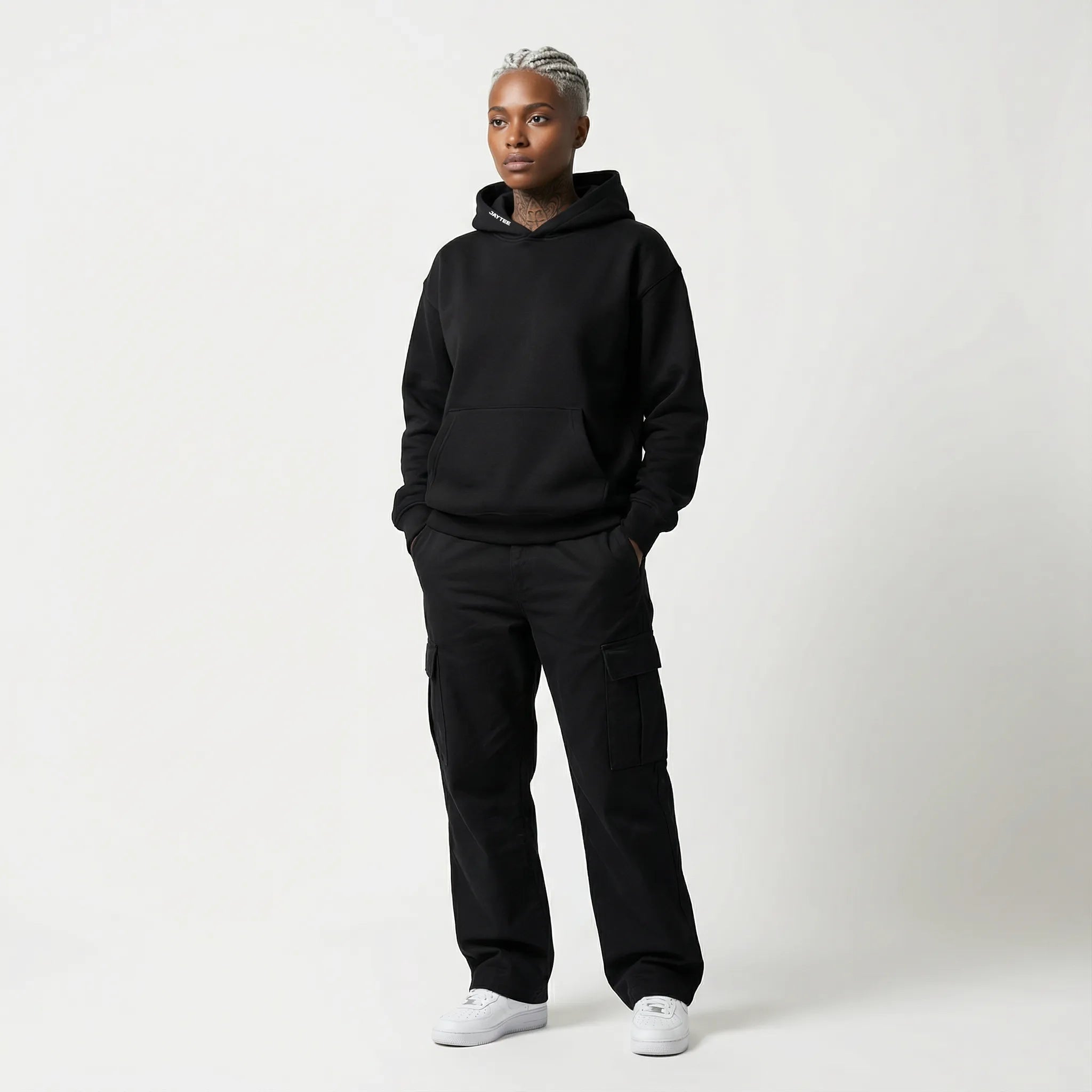 Person wearing a black JAYTEE hoodie and pants on a white background