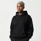 Person wearing a black JAYTEE hoodie and pants on a white background