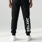 Person wearing a black JAYTEE tracksuit on a white background