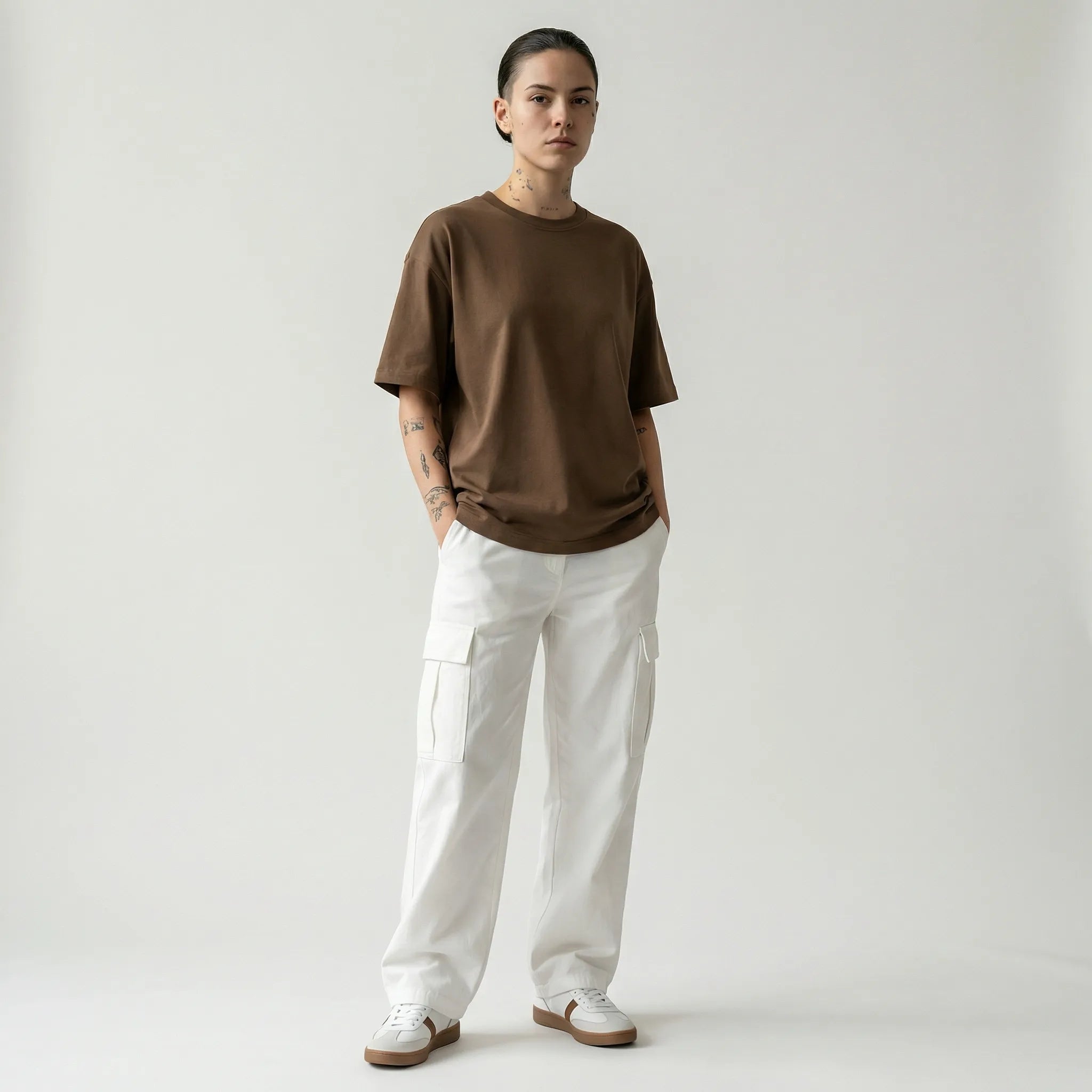 Person wearing a toffee JAYTEE t-shirt and white pants on a plain background