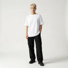 Person wearing a white JAYTEE t-shirt and black pants on a plain background