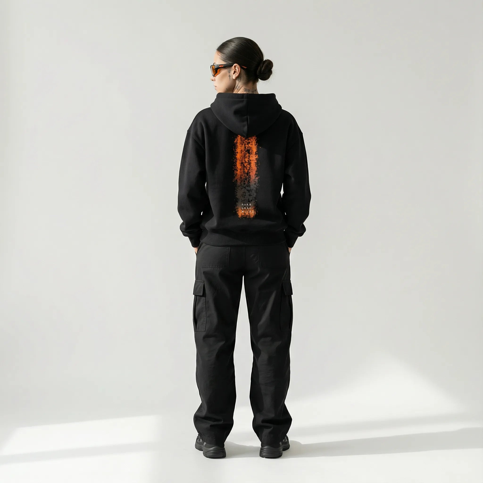 Person wearing a black JAYTEE hoodie with a unique design on the back against a white background