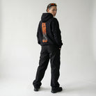 Person wearing a black JAYTEE hoodie with a unique design on the back against a white background