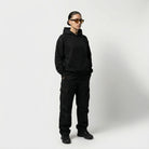 Person wearing a black JAYTEE hoodie and pants on a white background