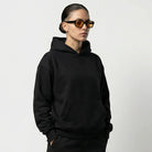 Person wearing a black JAYTEE hoodie and pants on a white background