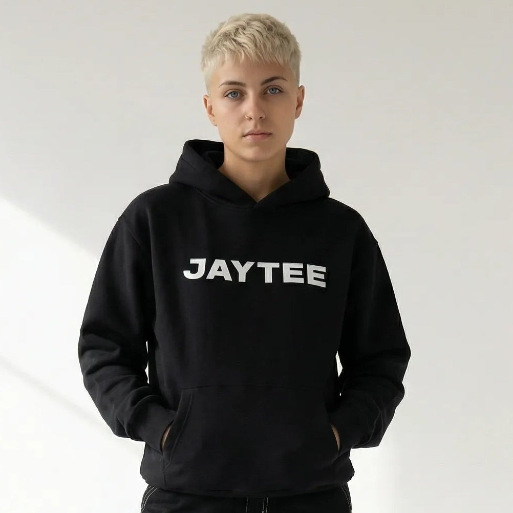 Person wearing a black JAYTEE hoodie with 'JAYTEE' branding and black cargo pants on a white background