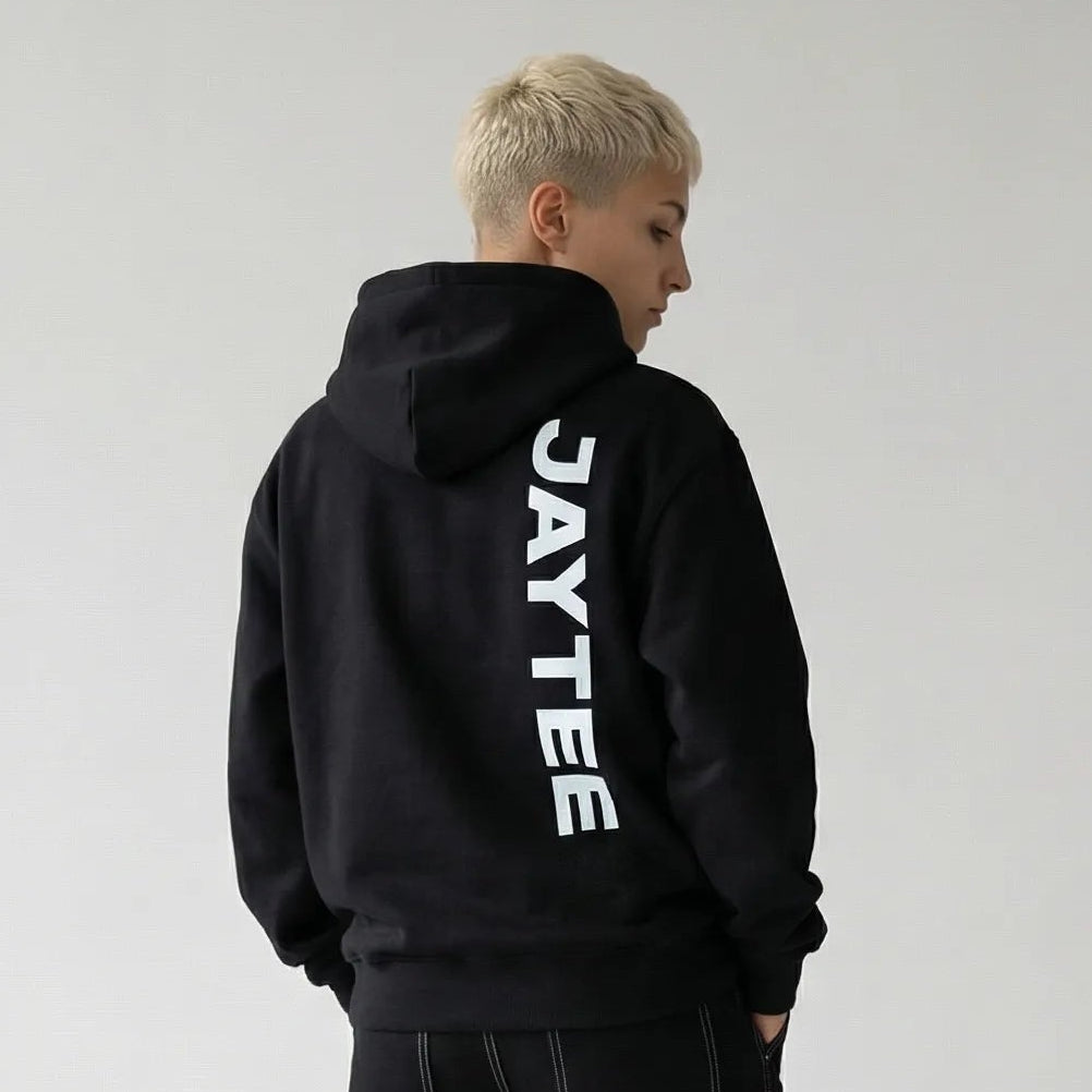 Person wearing a black JAYTEE hoodie with 'JAYTEE' branding on the back, standing against a plain white background.