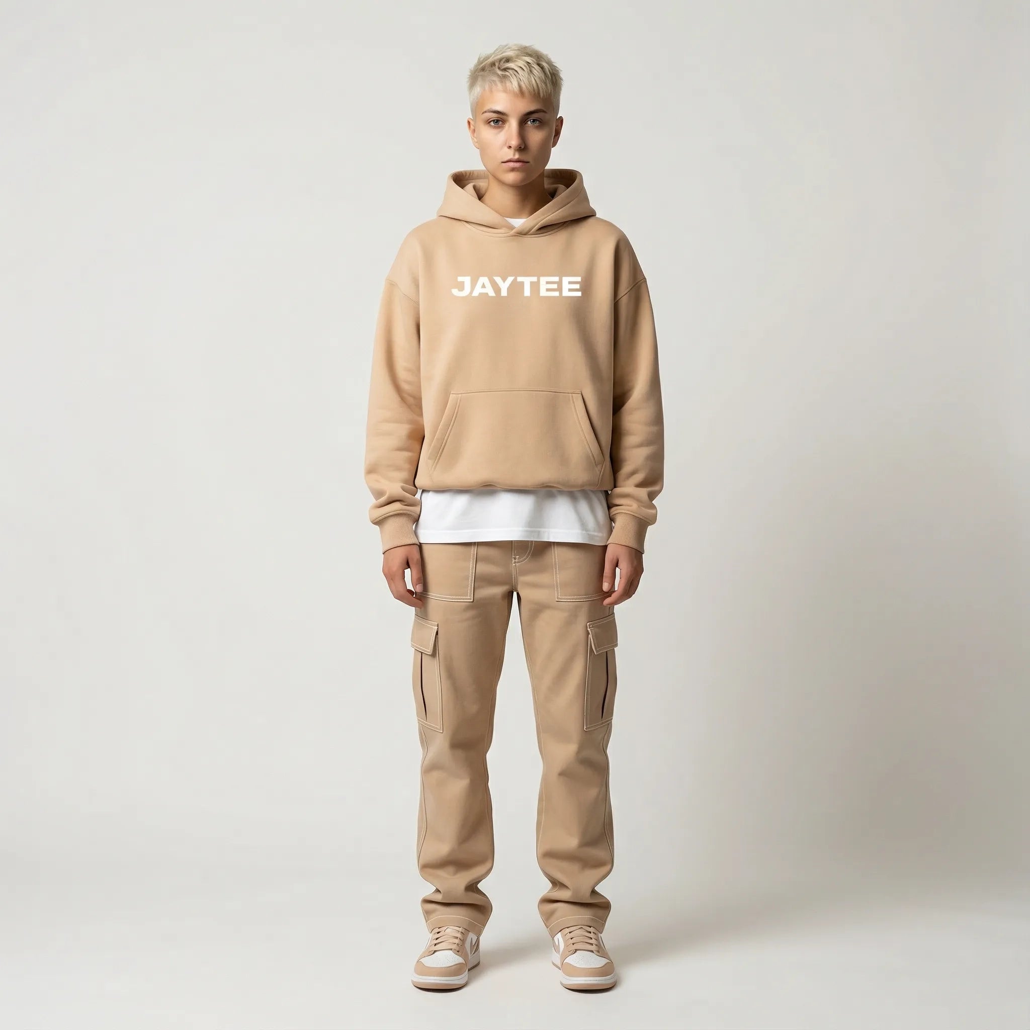 Person wearing a sand JAYTEE hoodie with white studio background