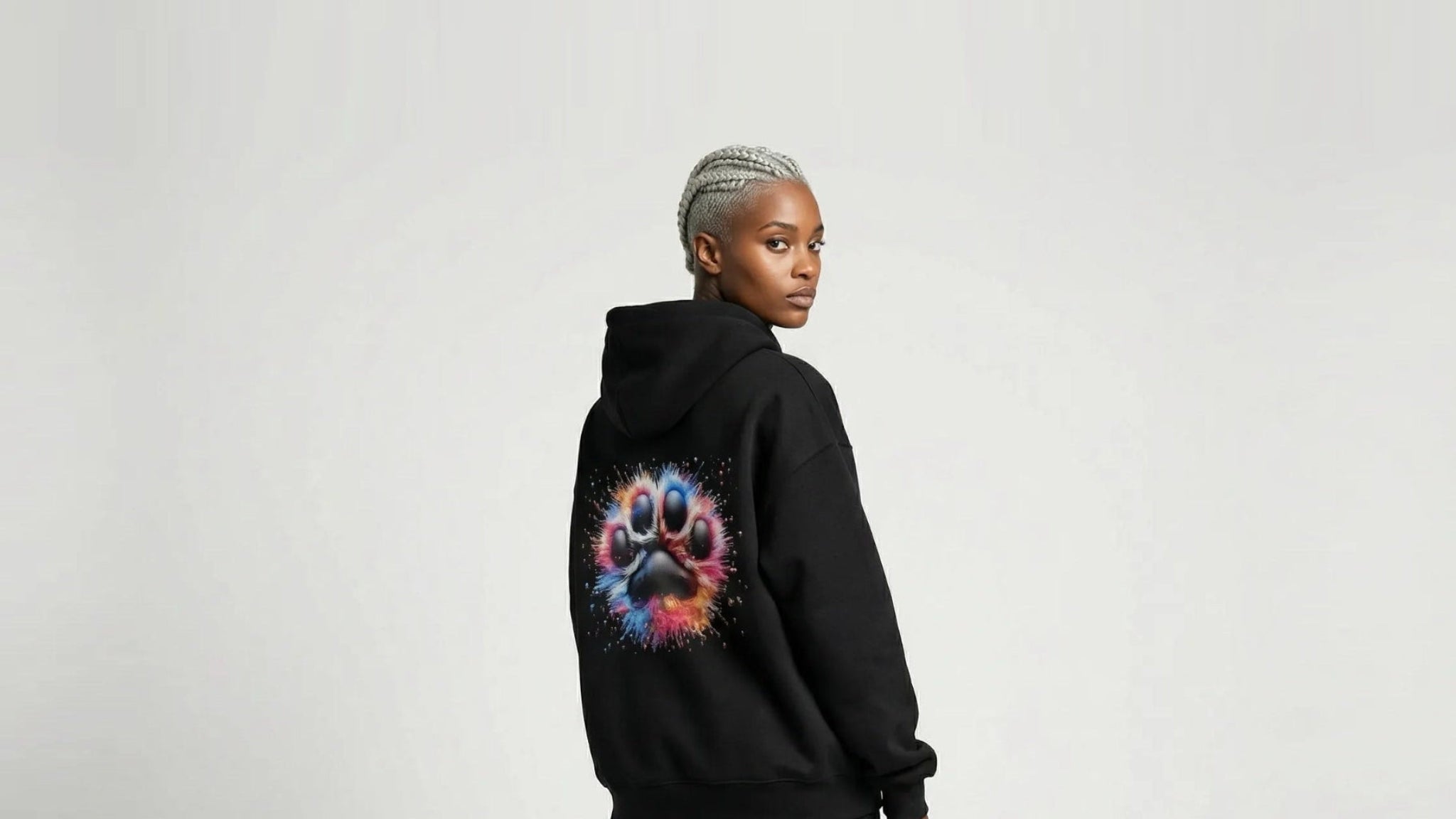 Person wearing a black hoodie with a colorful paw print design on the back, standing against a plain background.