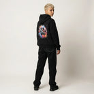 Person wearing a black hoodie with a colorful paw print design on the back, standing against a plain background.