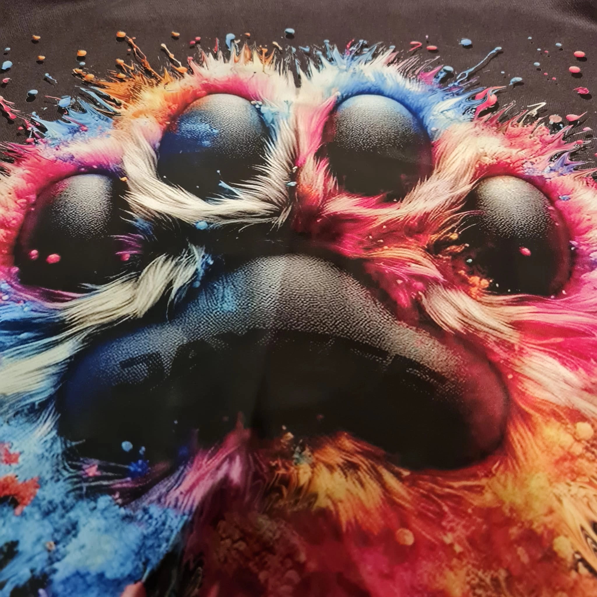 Colorful paw print with splashes of paint on a dark background