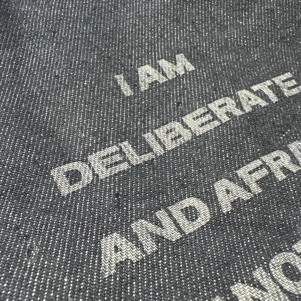 Text on a textured surface reading 'I AM DELIBERATE AND AFRAID OF NOTHING', with a focus on the word 'DELIBERATE'.